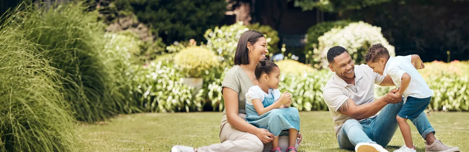 family sitting outside on grass playing and laughing