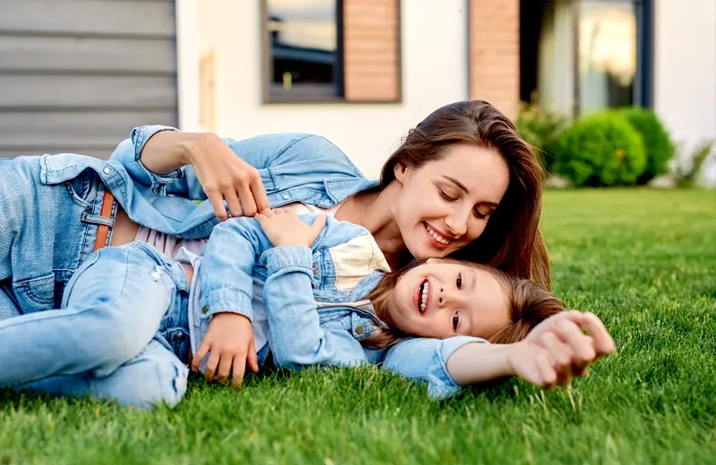 mom and daughter laying in green healthy grass